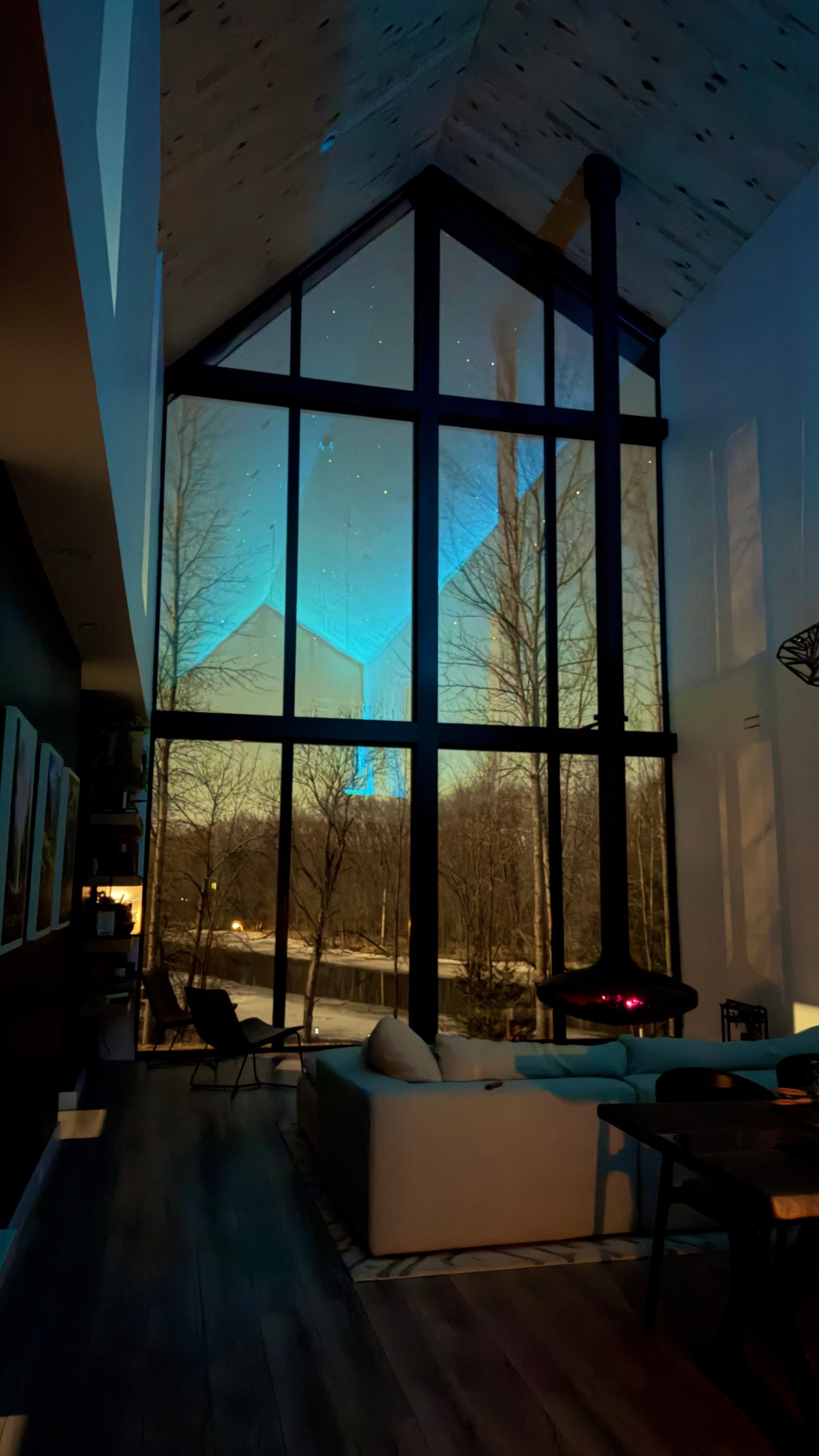 The Fernweh House exterior at dusk — glowing floor-to-ceiling windows against dark treeline