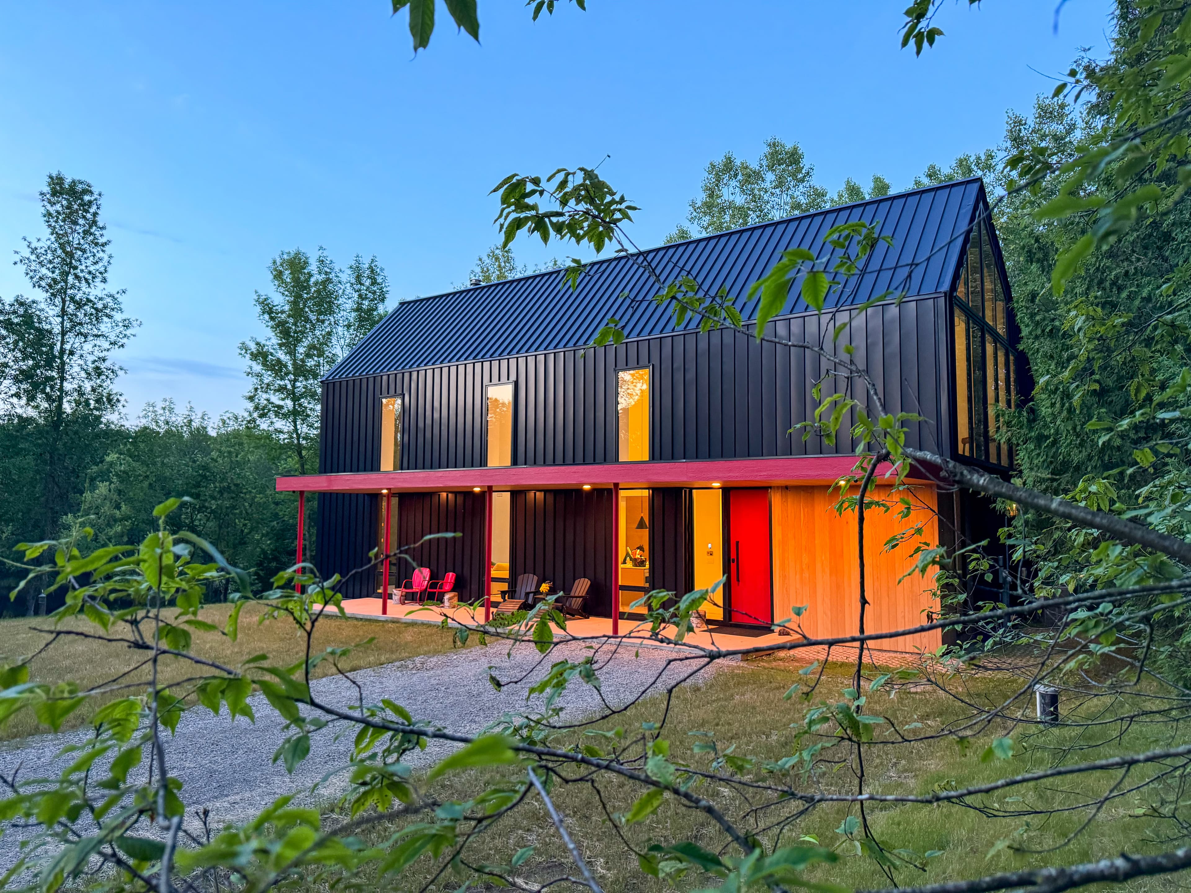 The Fernweh House exterior — metal siding and oak tree driveway