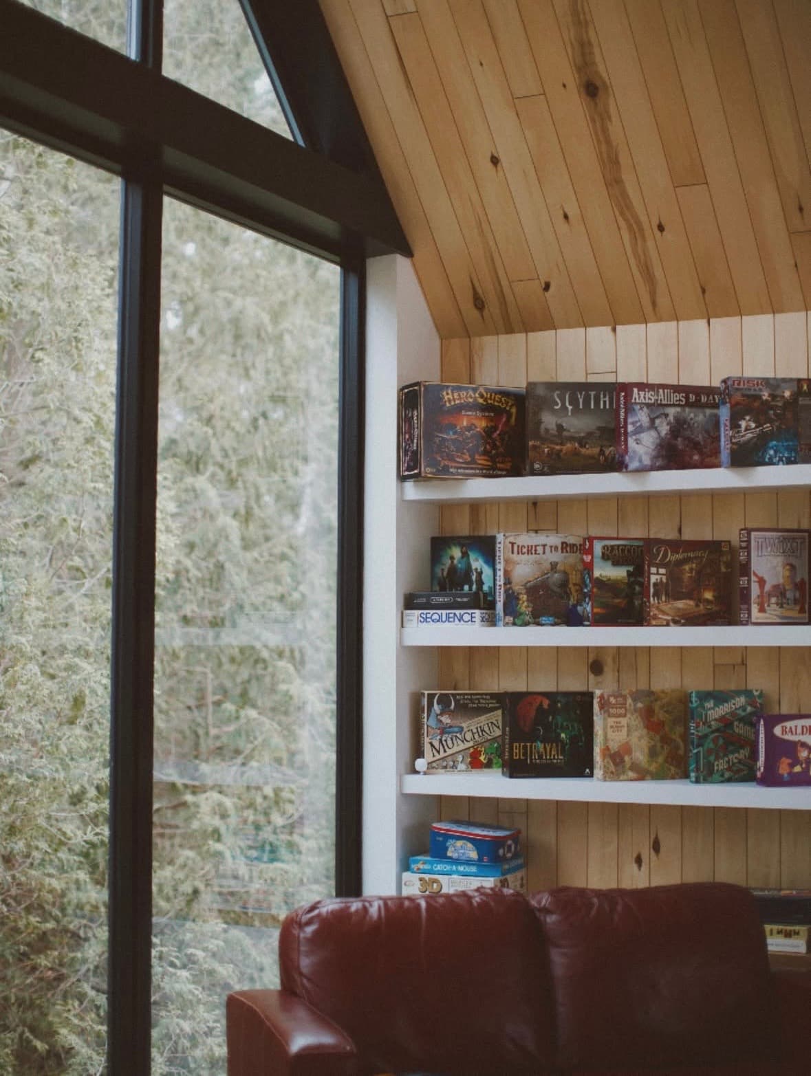Board game library — 30+ games under vaulted wood ceiling with river views
